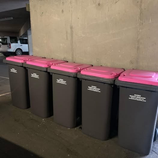 A row of Garbo commercial bins with distinctive hot pink lids